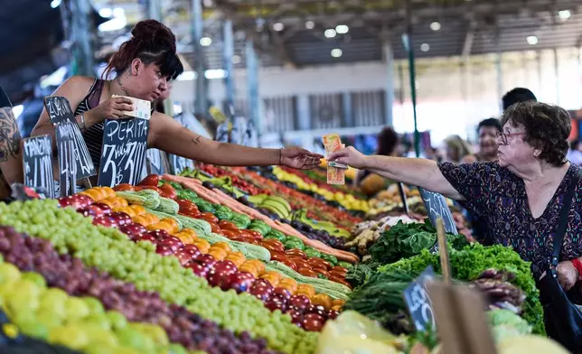 A customer pays for fruit at a greengrocer's stall in Buenos Aires, Argentina, Tuesday, Feb. 10, 2026. (AP Photo/Rodrigo Abd)