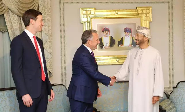 In this photo released by the Oman's Foreign Ministry, Steve Witkoff, White House special envoy, centre, shakes hands with Oman's Foreign Minister Sayyid Badr Albusaidi as Jared Kushner, left, looks on during their meeting prior to Iran and the U.S. negotiations, in Muscat, Oman, Friday, Feb. 6, 2026. (Oman Foreign Ministry via AP)