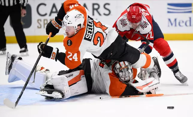 Philadelphia Flyers defenseman Nick Seeler (24) and goaltender Dan Vladar, bottom, battle for the puck against Washington Capitals right wing Brandon Duhaime (22) during the second period of an NHL hockey game, Wednesday, Feb. 25, 2026, in Washington. (AP Photo/Nick Wass)