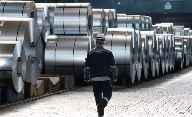 FILE - A steel worker walks beside steel coils during a visit of EU Commissioner for Prosperity and Industrial Strategy Stephane Sejourne at the Thyssenkrupp steelworks in Duisburg, Germany, after the EU Steel Action plan was presented, Thursday, March 20, 2025. (AP Photo/Martin Meissner, File)