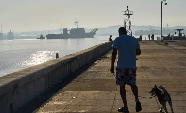 A man walks his dog along Havana Bay where the Mexican Navy ship Papaloapan arrives in Cuba, Thursday, Feb. 12, 2026. (AP Photo/Ramon Espinosa)