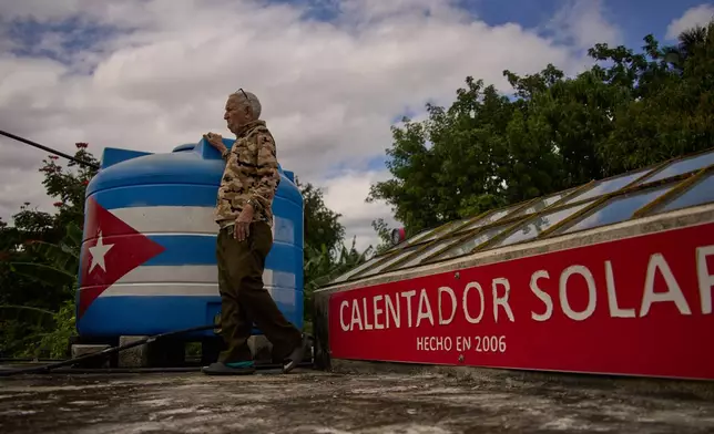 Felix Jose Morfi stands by his solar-powered water heater system he set up on his home's roof in Regla, Havana province, Cuba, Thursday. Jan. 29, 2026. (AP Photo/Ramon Espinosa)