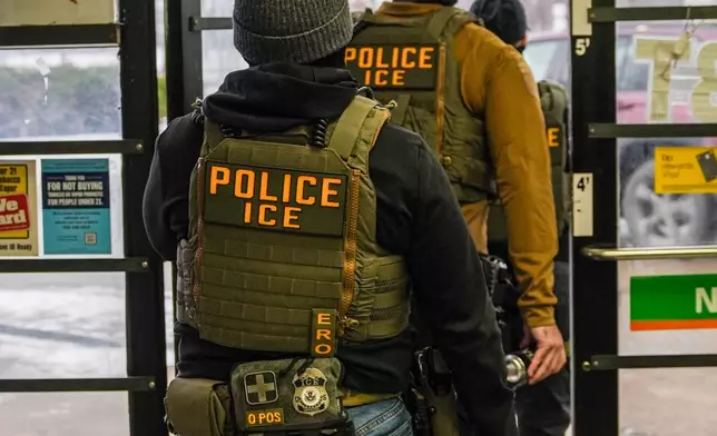 FILE - Immigration and Customs Enforcement (ICE) agents walk through a gas station in Minneapolis, Feb. 5, 2026. (AP Photo/Ryan Murphy)