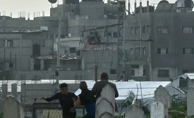 FILE - Three men, one already running away, watch from a graveyard as an Israeli military strike hits a building in the Zeitoun neighborhood of Gaza City, Feb. 6, 2026. (AP Photo/Jehad Alshrafi, File)