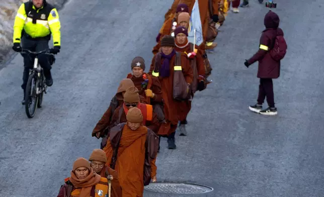 FILE - Buddhist monks who are participating in a Walk For Peace are escorted by Metropolitan Police Department officers as they walk along the C&amp;O Canal and Potomac River on Tuesday, Feb. 10, 2026, in Washington. (AP Photo/Mark Schiefelbein, File)