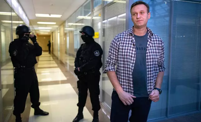FILE - Russian opposition leader Alexei Navalny speaks to the media in front of security officers standing guard at the Foundation for Fighting Corruption office in Moscow, Russia, Thursday, Dec. 26, 2019. (AP Photo/Alexander Zemlianichenko, File)