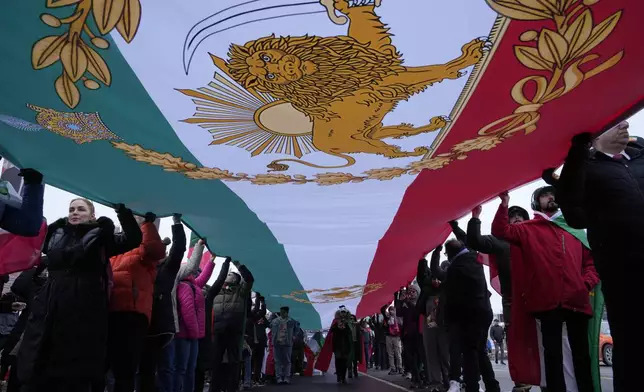 Carrying a huge lion and sun flag, supporters of Iran's exiled Crown Prince Reza Pahlavi attend a demonstration in Toronto, Saturday, Feb. 14, 2026. (AP Photo/Kamran Jebreili)