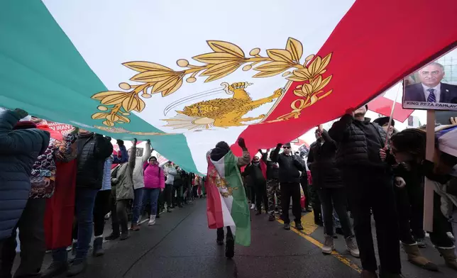 Carrying a huge lion and sun flag, supporters of Iran's exiled Crown Prince Reza Pahlavi attend a demonstration in Toronto, Saturday, Feb. 14, 2026. (AP Photo/Kamran Jebreili)