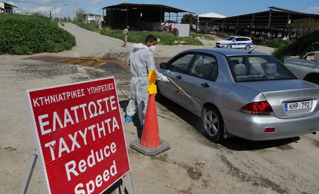 An employee sprays a car inside a blocked section of a livestock zone containing thousands of goats, sheep, and cows following an outbreak of foot-and-mouth disease in the Kelia area near Larnaca, Cyprus, Wednesday, Feb. 25, 2026. (AP Photo/Petros Karadjias)