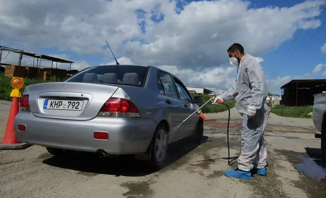 An employee sprays a car inside a blocked section of a livestock zone containing thousands of goats, sheep, and cows following an outbreak of foot-and-mouth disease in the Kelia area near Larnaca, Cyprus, Wednesday, Feb. 25, 2026. (AP Photo/Petros Karadjias)