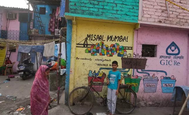A boy stands beside a wall that shows a mural by the Rouble Nagi Art Foundation in the Dhobi Ghat area of Mumbai, India, Thursday, Feb. 5, 2026. (AP Photo/Rafiq Maqbool)