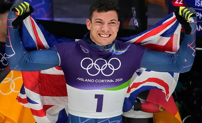 Britain's gold medalist Matt Weston celebrates as he arrives at the finish during a men's skeleton run at the 2026 Winter Olympics, in Cortina d'Ampezzo, Italy, Friday, Feb. 13, 2026. (AP Photo/Alessandra Tarantino)