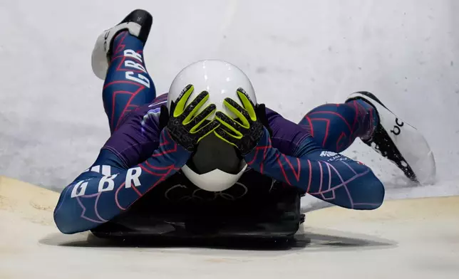 Britain's gold medalist Matt Weston celebrates as he arrives at the finish during a men's skeleton run at the 2026 Winter Olympics, in Cortina d'Ampezzo, Italy, Friday, Feb. 13, 2026. (AP Photo/Aijaz Rahi)