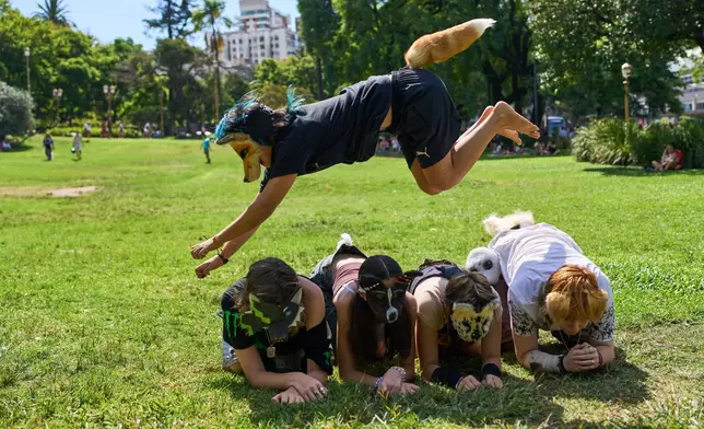 A youth jumps over other therians, people who say they identify as non-human animals, during a gathering in a square in Buenos Aires, Argentina, Sunday, Feb. 22, 2026. (AP Photo/Rodrigo Abd)