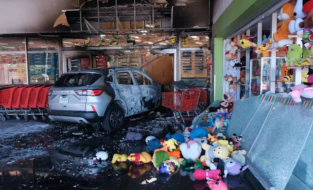 A charred vehicle sits at a damaged supermarket in Guadalajara, Jalisco state, Mexico, Sunday, Feb. 22, 2026, after the death of the leader of the Jalisco New Generation Cartel, Nemesio Rubén Oseguera Cervantes, known as "El Mencho." (AP Photo/Alejandra Leyva)