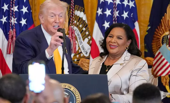 President Donald Trump speaks as White House pardon czar Alice Johnson listens during a Black History Month event in the East Room of the White House, Wednesday, Feb. 18, 2026, in Washington. (AP Photo/Nathan Howard)