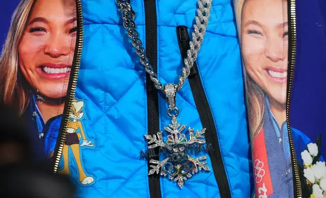 Snoop Dogg wears a chain and jacket displaying United States' Chloe Kim during the women's snowboarding halfpipe finals at the 2026 Winter Olympics, in Livigno, Italy, Thursday, Feb. 12, 2026. (AP Photo/Lindsey Wasson)