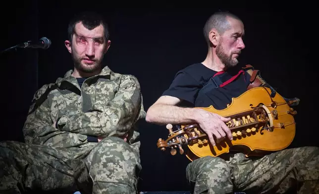 Andrii Onopriienko, left, and Taras Kozuk, war veterans who sustained severe injuries in combat during Russia's full-scale invasion in Ukraine, relax before the premiere of an adaptation of Ivan Kotliarevskyi’s “Eneida,” a Ukrainian reimagining of Virgil’s “Aeneid,” in Kyiv, Ukraine, Thursday, Feb. 19, 2026. (AP Photo/Efrem Lukatsky)
