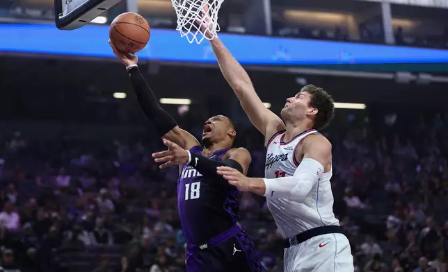 Sacramento Kings guard Russell Westbrook (18) draws the foul on Los Angeles Clippers center Brook Lopez, right, during the first half of an NBA basketball game Friday, Feb. 6, 2026, in Sacramento, Calif. (AP Photo/Sara Nevis)