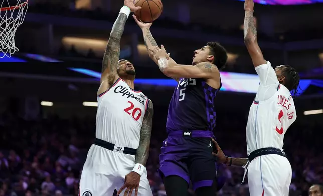 Sacramento Kings guard Nique Clifford, center, goes up to shoot between Los Angeles Clippers forwards John Collins (20) and Derrick Jones Jr., right, during the first half of an NBA basketball game Friday, Feb. 6, 2026, in Sacramento, Calif. (AP Photo/Sara Nevis)