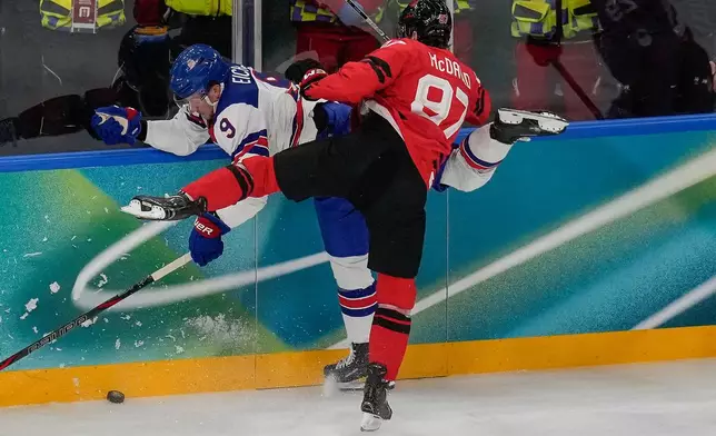 Canada's Connor McDavid (97) checks United States' Jack Eichel (9) into the wall during the first period of the men's ice hockey gold medal game at the 2026 Winter Olympics, in Milan, Italy, Sunday, Feb. 22, 2026. (AP Photo/Luca Bruno)