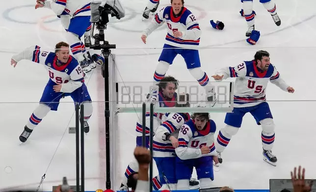 The United States celebrates after a sudden-death overtime goal by United States' Jack Hughes (86) against Canada during the men's ice hockey gold medal game at the 2026 Winter Olympics, in Milan, Italy, Sunday, Feb. 22, 2026. (AP Photo/Luca Bruno)