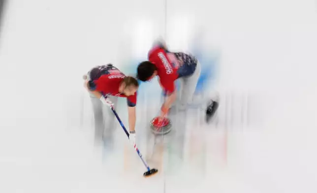 United States' Luc Violette and Aidan Oldenburg sweep ahead of a stone during a men's curling round robin match against China at the 2026 Winter Olympics, in Cortina d'Ampezzo, Italy, Tuesday, Feb. 17, 2026. (AP Photo/David J. Phillip)