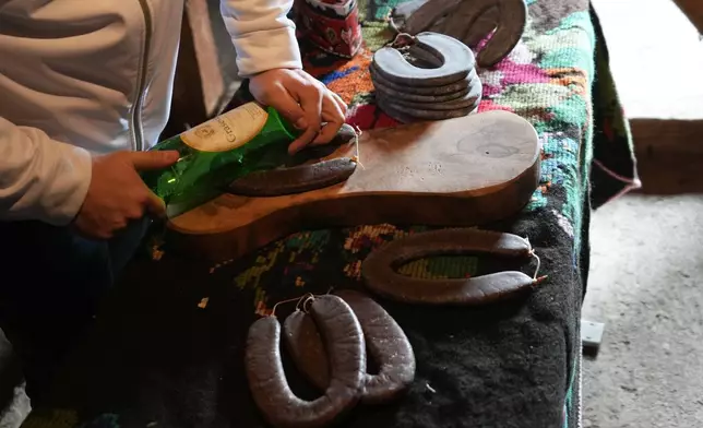 Misa Rajic irons sausage using a glass bottle in the attic of his home in Pirot, Serbia, on Feb. 13, 2026. (AP Photo/Darko Vojinovic)