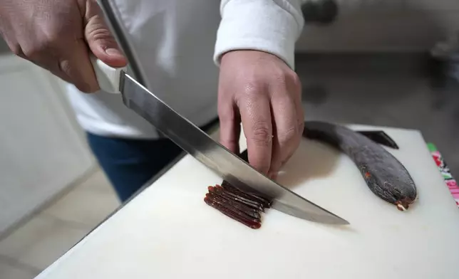 Misa Rajic prepares ironed sausage at his home in Pirot, Serbia, on Feb. 13, 2026. (AP Photo/Darko Vojinovic)
