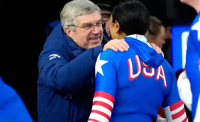 Former IOC President Thomas Bach, left, talks to United States' Elana Meyers Taylor at the finish during a two women bobsled run at the 2026 Winter Olympics, in Cortina d'Ampezzo, Italy, Friday, Feb. 20, 2026. (AP Photo/Alessandra Tarantino)