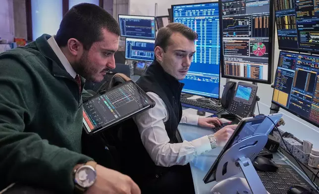 Traders Drew Cohen, left, and Dylan Halvorsan work on the floor of the New York Stock Exchange, Monday, Jan. 26, 2026. (AP Photo/Richard Drew)