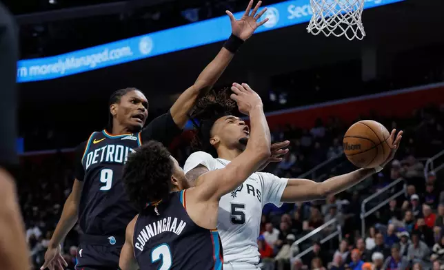 San Antonio Spurs guard Stephon Castle (5) goes to the basket past Detroit Pistons guards Ausar Thompson (9) and Cade Cunningham (2) during the first half of an NBA basketball game Monday, Feb. 23, 2026, in Detroit. (AP Photo/Duane Burleson)