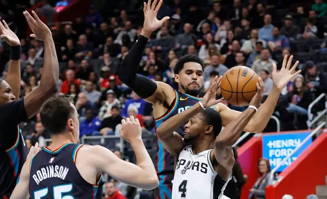 San Antonio Spurs guard De'aaron Fox (4) looks to pass the ball against Detroit Pistons forward Tobias Harris, top right, and forward Duncan Robinson, front left, during the first half of an NBA basketball game Monday, Feb. 23, 2026, in Detroit. (AP Photo/Duane Burleson)
