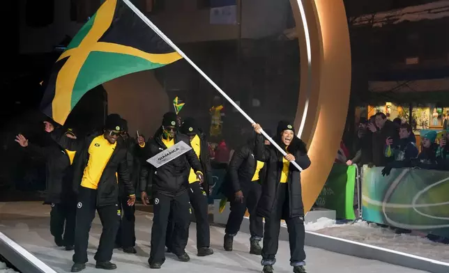 Mica Moore, flag bearer of Jamaica, leads her team in during the Olympic opening ceremony at the 2026 Winter Olympics, in Cortina d'Ampezzo, Italy, Friday, Feb. 6, 2026. (AP Photo/Misper Apawu)