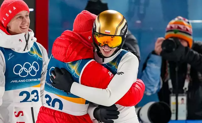 Kacper Tomasiak, of Poland, right, celebrates with teammates Kamil Stoch and Pawel Wasek, left, after his final round jump during the ski jumping men's normal hill individual at the 2026 Winter Olympics, in Predazzo, Italy, Monday, Feb. 9, 2026. (AP Photo/Matthias Schrader)