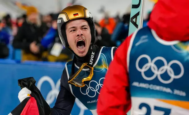 Philipp Raimund, of Germany, celebrates after winning the gold medal in the ski jumping men's normal hill individual at the 2026 Winter Olympics, in Predazzo, Italy, Monday, Feb. 9, 2026. (AP Photo/Evgeniy Maloletka)