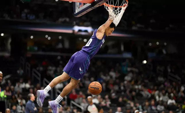 Charlotte Hornets guard Josh Green (10) swings from the rim after dunking during the first half of an NBA basketball game against the Washington Wizards, Sunday, Feb. 22, 2026, in Washington. (AP Photo/Nick Wass)