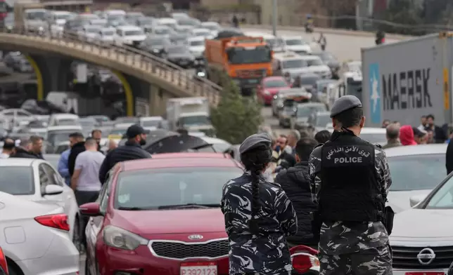 Lebanese police stand in front of taxi drivers who block a main highway with their cars during a protest against the increased taxes and gasoline prices issued by the Lebanese Cabinet on Monday, in Beirut, Lebanon, Tuesday, Feb. 17, 2026. (AP Photo/Hussein Malla)