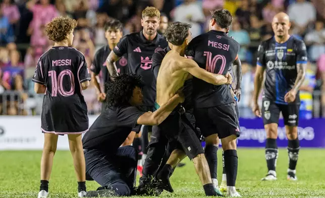 A fan who got onto the field grabs Inter Miami's Lionel Messi at the end of an international friendly soccer match against Ecuador's Independiente del Valle in Bayamon, Puerto Rico, Thursday, Feb. 26, 2026. (AP Photo/Alejandro Granadillo)