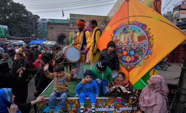 Children pose for a photograph on a truck decorated with colourful kites ahead of the three-day kite flying Basant festival celebration, in Lahore, Pakistan, Tuesday, Feb. 3, 2026. (AP Photo/K.M. Chaudary)