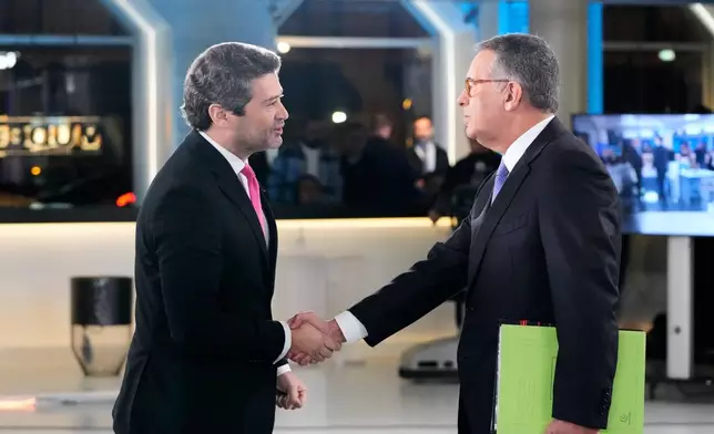 Presidential candidates Antonio Jose Seguro, of the center-left Socialist Party, right, and Andre Ventura, of the populist Chega party, shake hands before a television debate ahead of the Feb. 8 presidential election, in Lisbon, Tuesday, Jan. 27, 2026. (AP Photo/Armando Franca)
