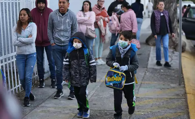 Students arrive to school wearing face masks due to a measles outbreak in Guadalajara, Mexico, Friday, Feb. 6, 2026. (AP Photo/Fernando Llano)