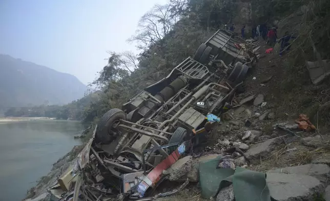 The wreckage of a bus is seen on the bank of the Trishuli River after it drove off a mountain highway near Benighat, west of the capital, Kathmandu, Nepal, Monday, Feb. 23, 2026. (AP Photo/Bijay Rai)