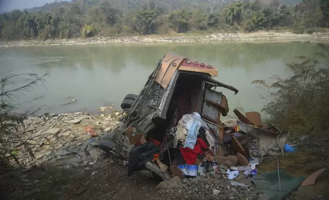 The wreckage of a bus is seen on the bank of the Trishuli River after it drove off a mountain highway near Benighat, west of the capital, Kathmandu, Nepal, Monday, Feb. 23, 2026. (AP Photo/Bijay Rai)