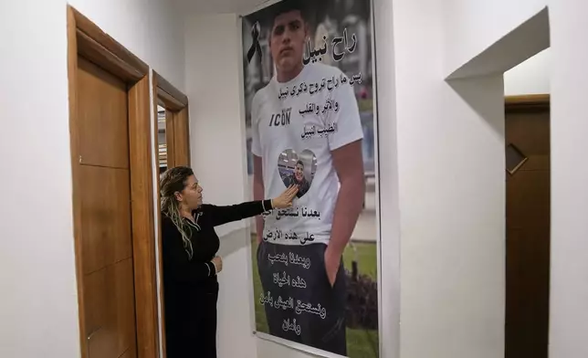 Raweah Safiya palms a poster bearing the image of her son, Nabil, who was shot dead in last November in a case of mistaken identity, a victim of gang-related violence, in Kafr Yasif, northern Israel, Sunday, Jan. 18, 2026. (AP Photo/Mahmoud Illean)