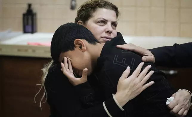 Raweah Safiya consoles one of her children as he cries over the death of his brother, Nabil Safiya, at the family's home in Kafr Yasif, northern Israel, Sunday, Jan. 18, 2026. (AP Photo/Mahmoud Illean)