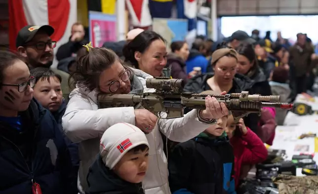 A woman aims a rifle aboard a naval vessel during a public day in Nuuk, Greenland, on Saturday, Jan. 24, 2026. (AP Photo/Evgeniy Maloletka)