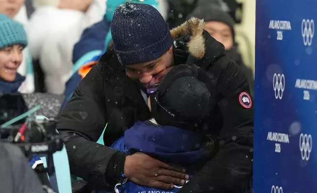 Cleveland Browns' Myles Garrett and United States' Chloe Kim kiss after Kim won the silver medal in the women's snowboarding halfpipe finals at the 2026 Winter Olympics, in Livigno, Italy, Thursday, Feb. 12, 2026. (AP Photo/Abbie Parr)