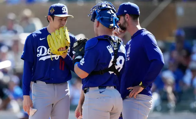Los Angeles Dodgers starting pitcher Roki Sasaki (11), of Japan, gets a visit from Dodgers pitching coach Mark Prior, right, and Dodgers catcher Dalton Rushing during the first inning of a spring training baseball game against the Arizona Diamondbacks Wednesday, Feb. 25, 2026, in Scottsdale, Ariz. (AP Photo/Ross D. Franklin)