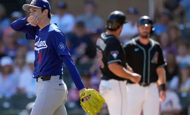 Los Angeles Dodgers starting pitcher Roki Sasaki (11), of Japan, pauses near home plate after Arizona Diamondbacks' Nolan Arenado, center, and Tim Tawa scored runs during the first inning of a spring training baseball game Wednesday, Feb. 25, 2026, in Scottsdale, Ariz. (AP Photo/Ross D. Franklin)